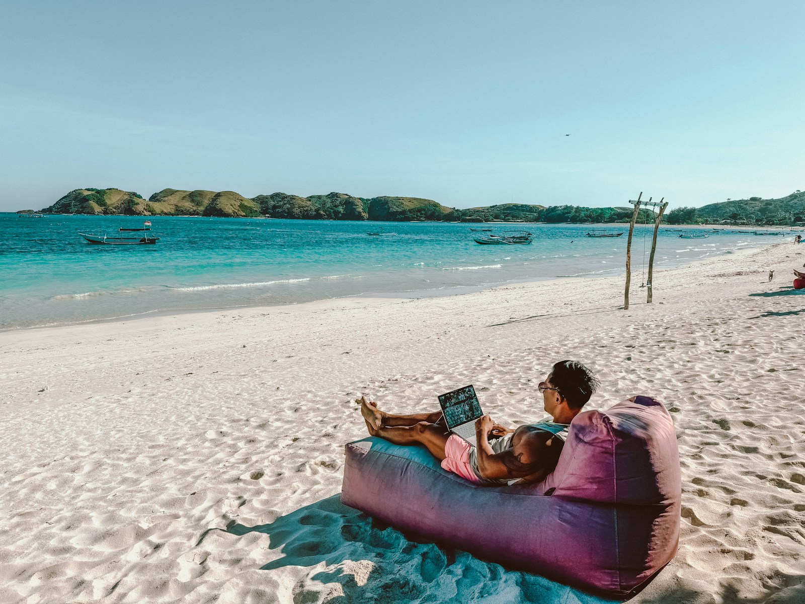 Photo by Johnny Africa a man sitting on a bean bag on the beach